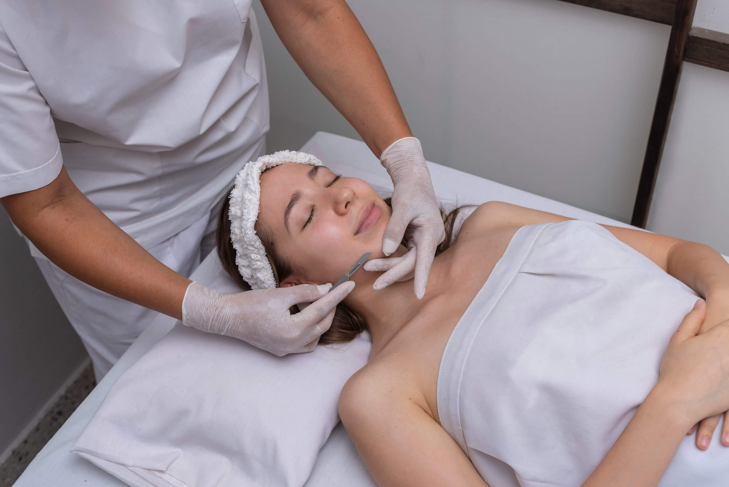 Beautiful young woman lying on a stretcher in an aesthetic center performing dermaplaning technique | Casa Glow Inc in East 22nd Street New York