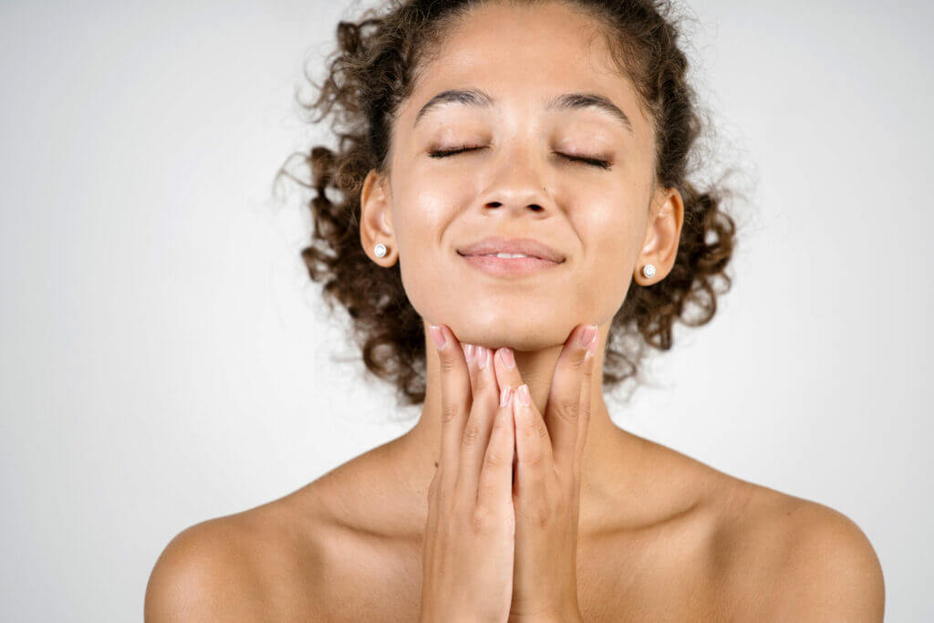 Bodycare and skincare concept. Portrait of happy young adult mulatto woman with naked shoulders touching face, applying lifting cream on neck and chin isolated on white background with copy space, Reclaiming Youthful Beauty The Power of Skin Tightening | Casa Glow Inc in East 22nd Street New York